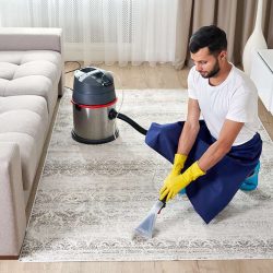 Man Cleaning Carpet In The Living Room Using Vacuum Cleaner At Home. Cleaning service concept